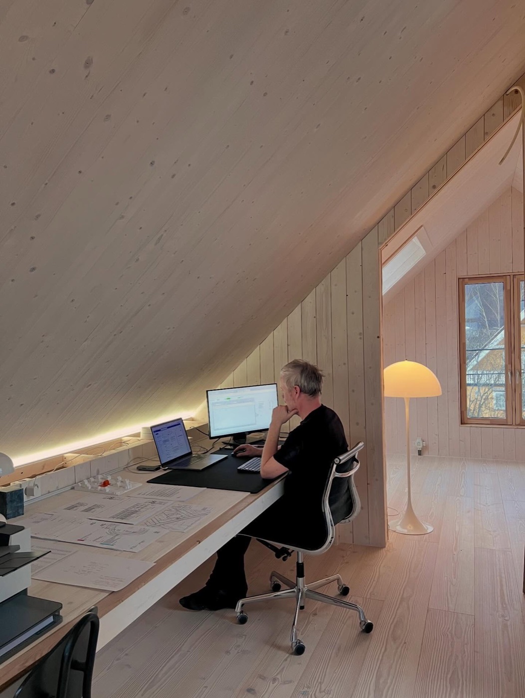 Emil Lockertsen ved arbeidsbordet under skråtaket i massivtre