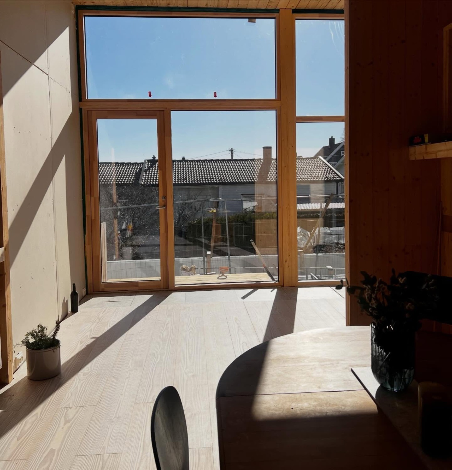 Vinterhage i massivtre med store vinduer og sol over gulvet